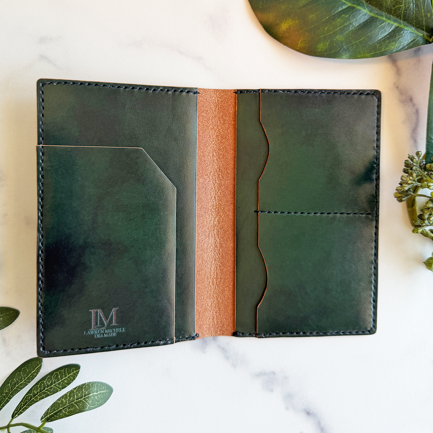 A green leather passport cover on a white marble countertop. It's open to show pockets for a passport, plane ticket, cash, and up to four credit cards.