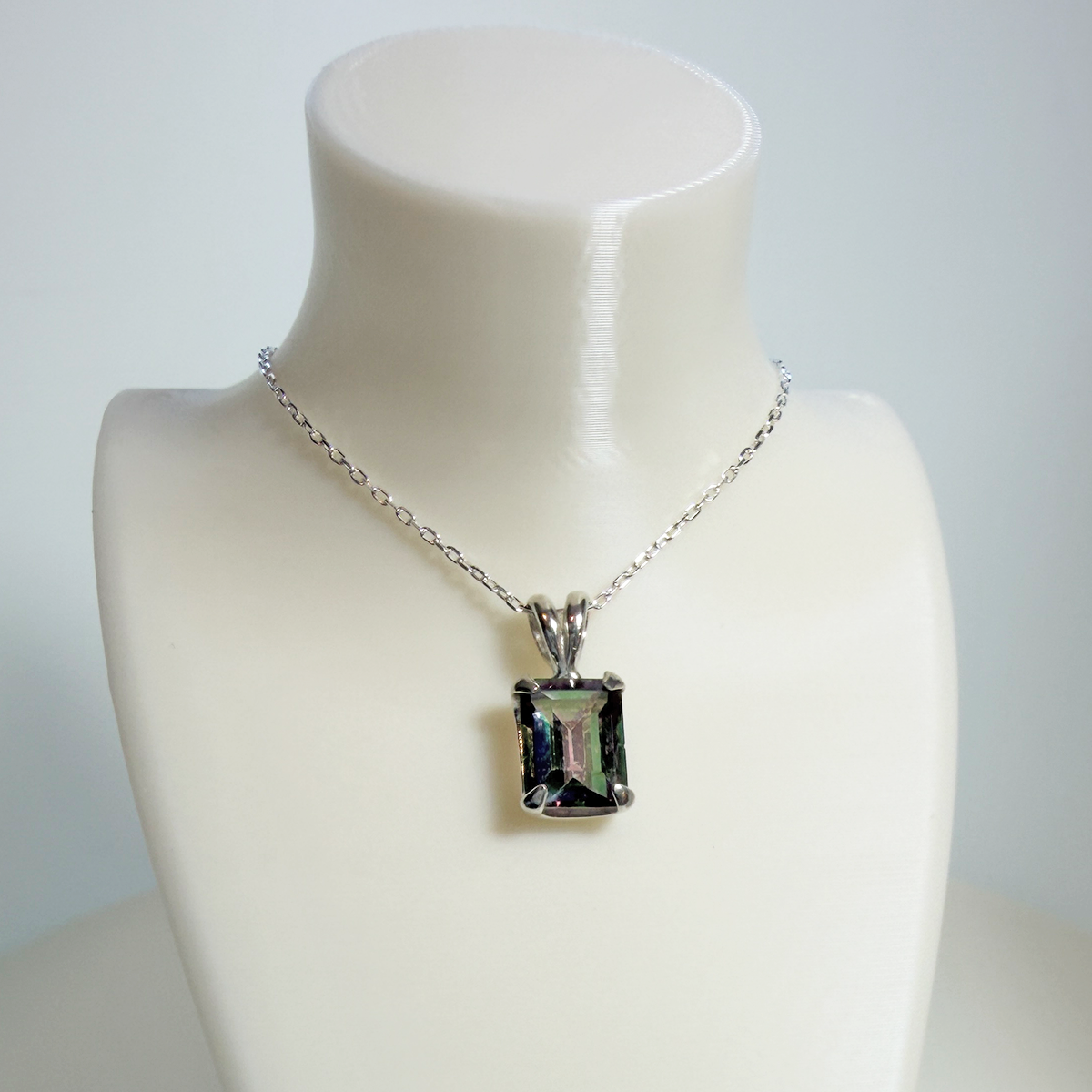 Mystic quartz sterling silver pendant necklace with thin silver chain on a mannequin bust against a plain background