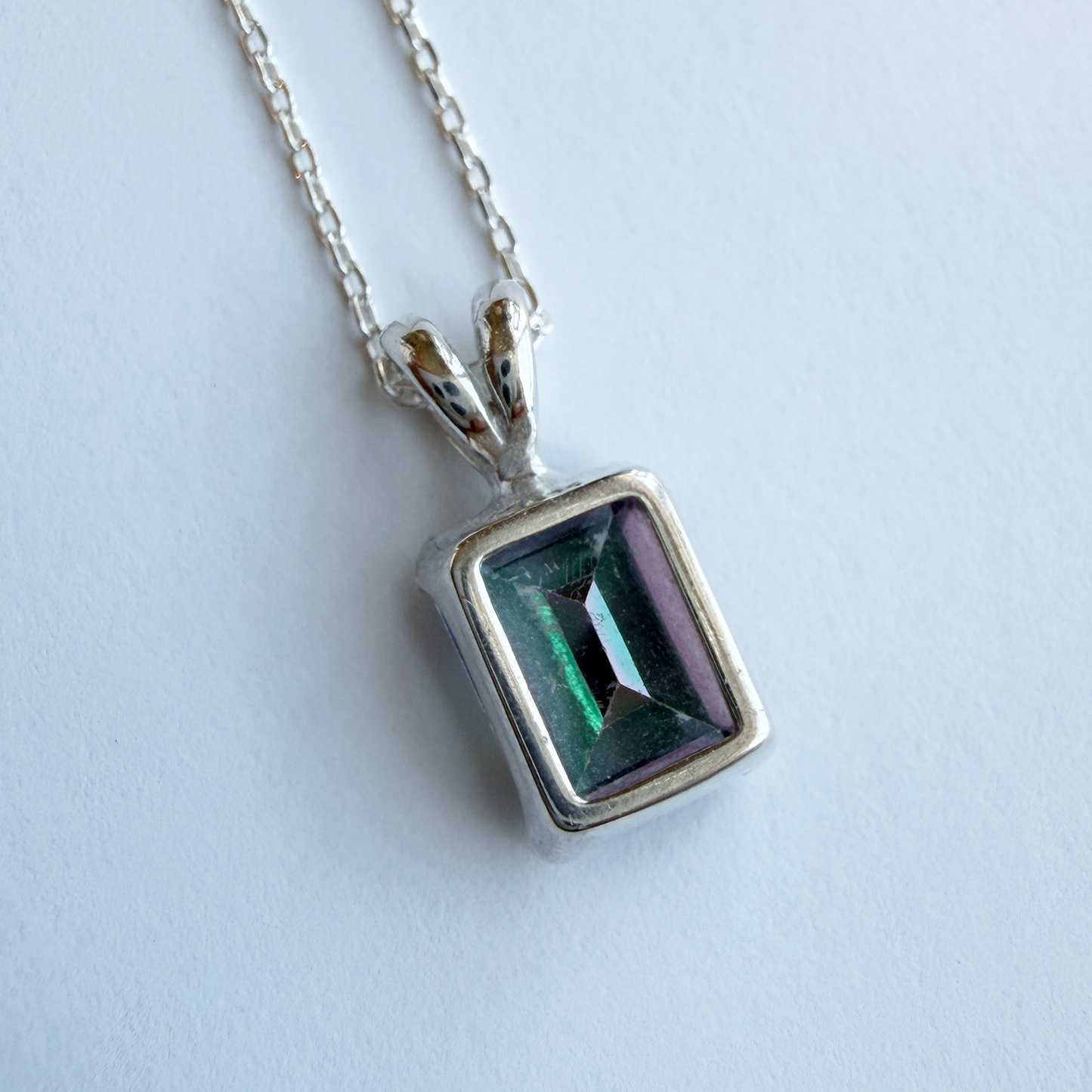 Silver pendant with a mystic quartz gemstone on a white background
