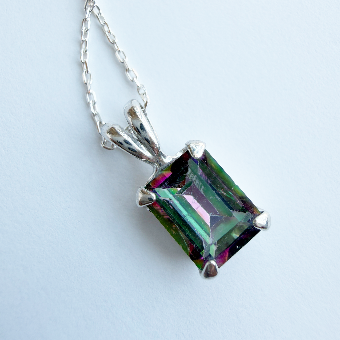 Multicolored mystic quartz gemstone pendant  with a sterling silver chain on a white background