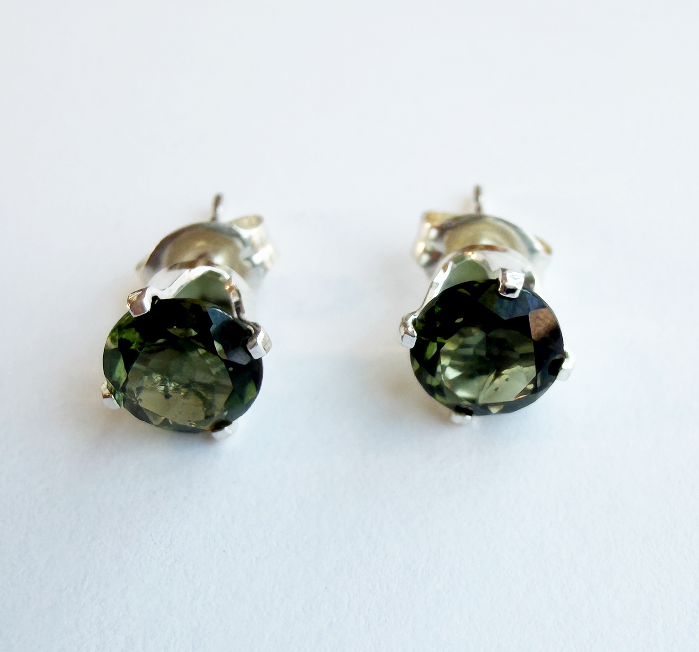 Pair of green Moldavite gemstone stud earrings on a white background