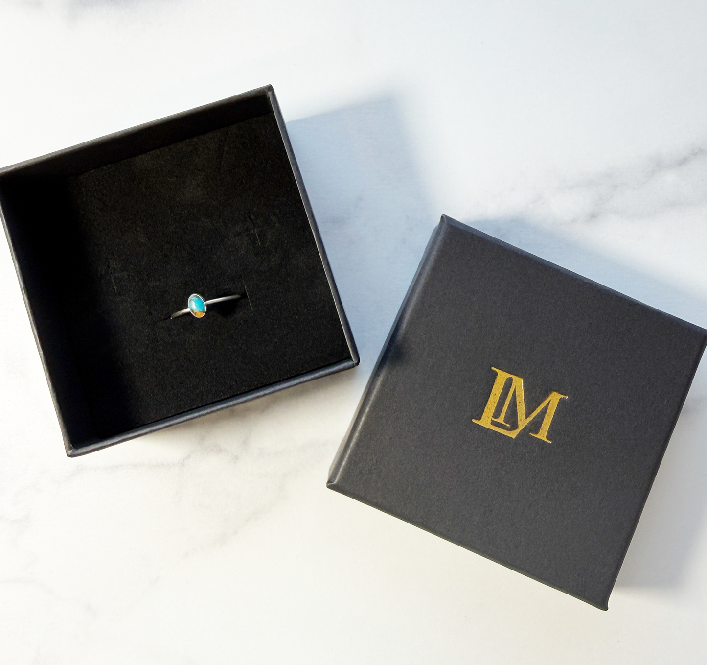 Jewelry box with a turquoise ring inside on a marble surface