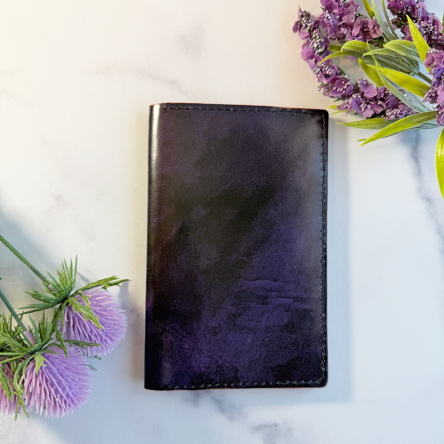A purple leather passport cover on a marble countertop. 