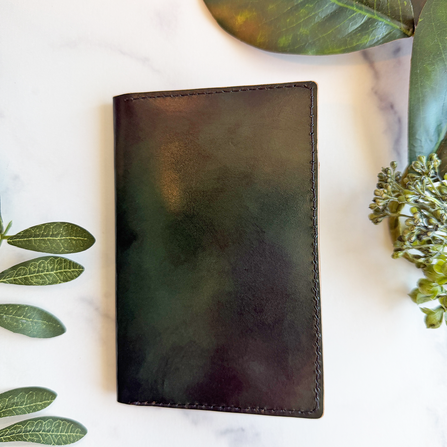 A green leather passport cover on a white marble countertop.