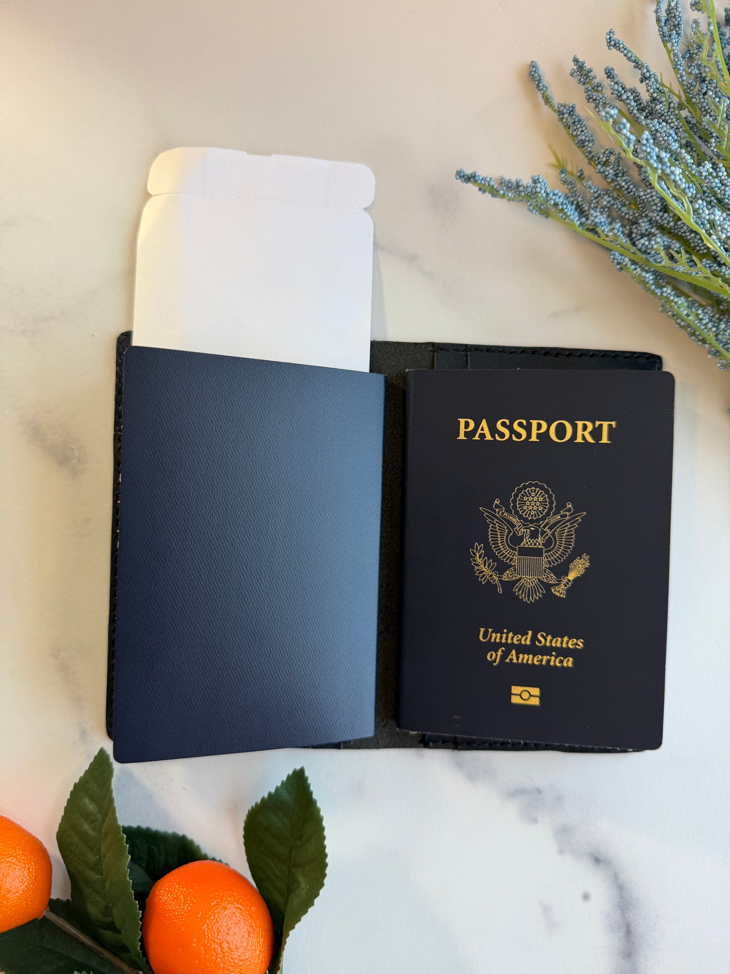A blue leather passport cover on a marble countertop. There are two passports and a plane ticket inside.
